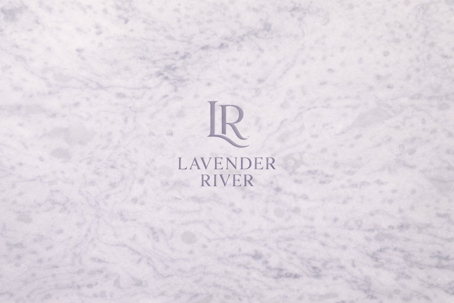 Lavender River monogram and wordmark embossed on a soft white-and-gray marble surface