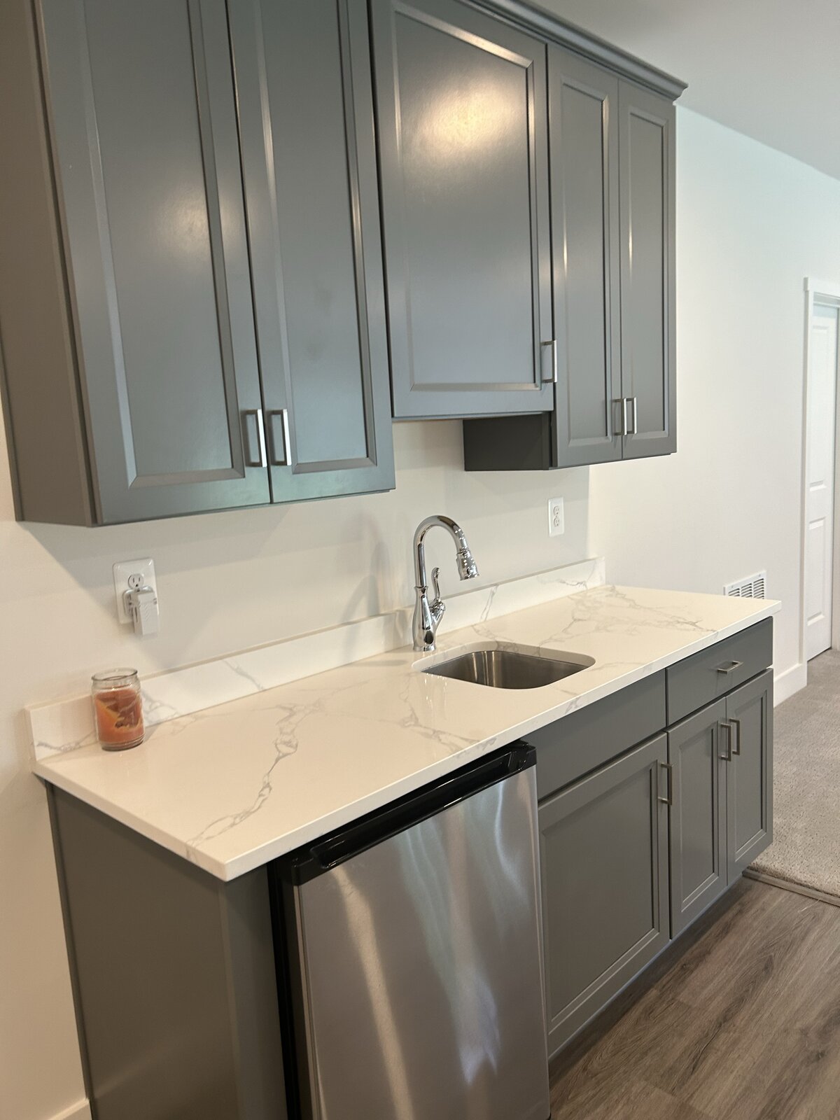 Sage green wet bar with shaker cabinets, calacatta quartz counter, undermount sink, beverage fridge, and a small candle
