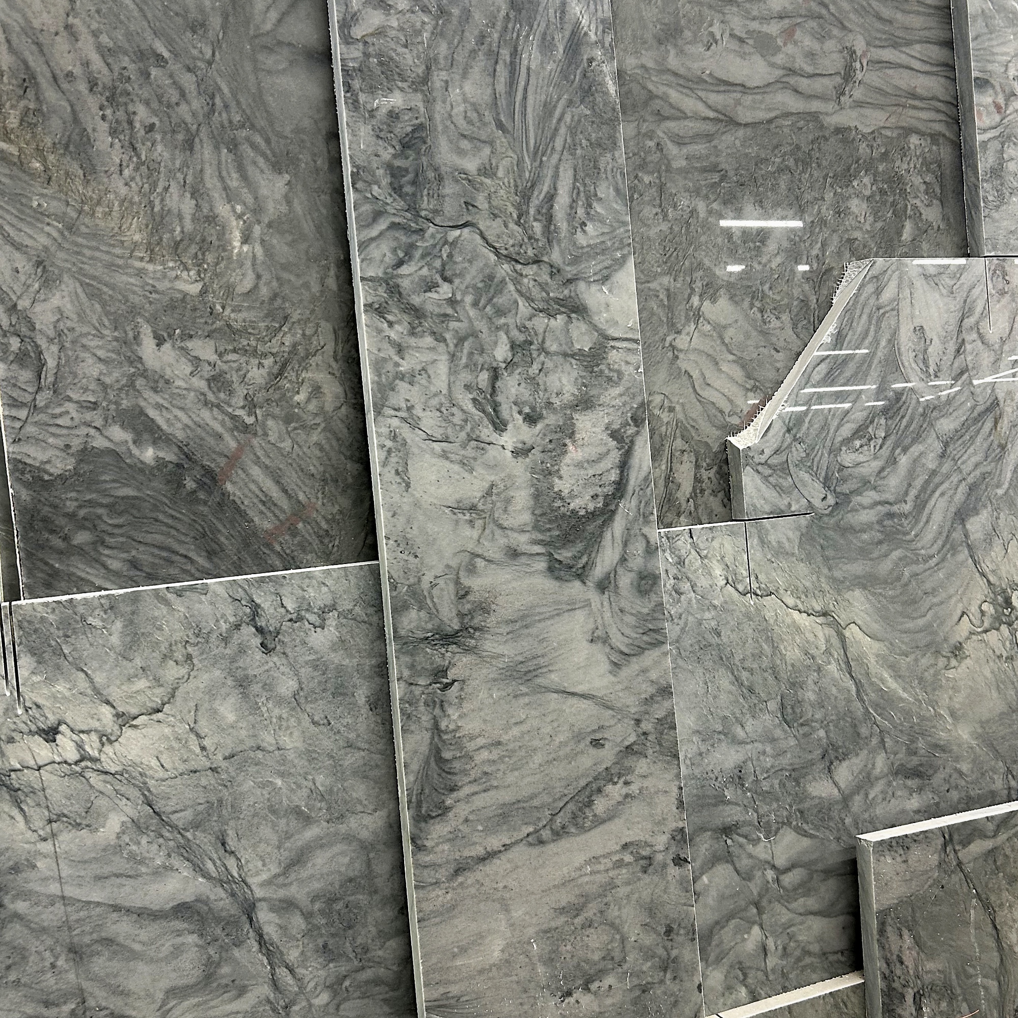 Gray quartzite slabs stacked at the warehouse — silver and charcoal with dramatic movement