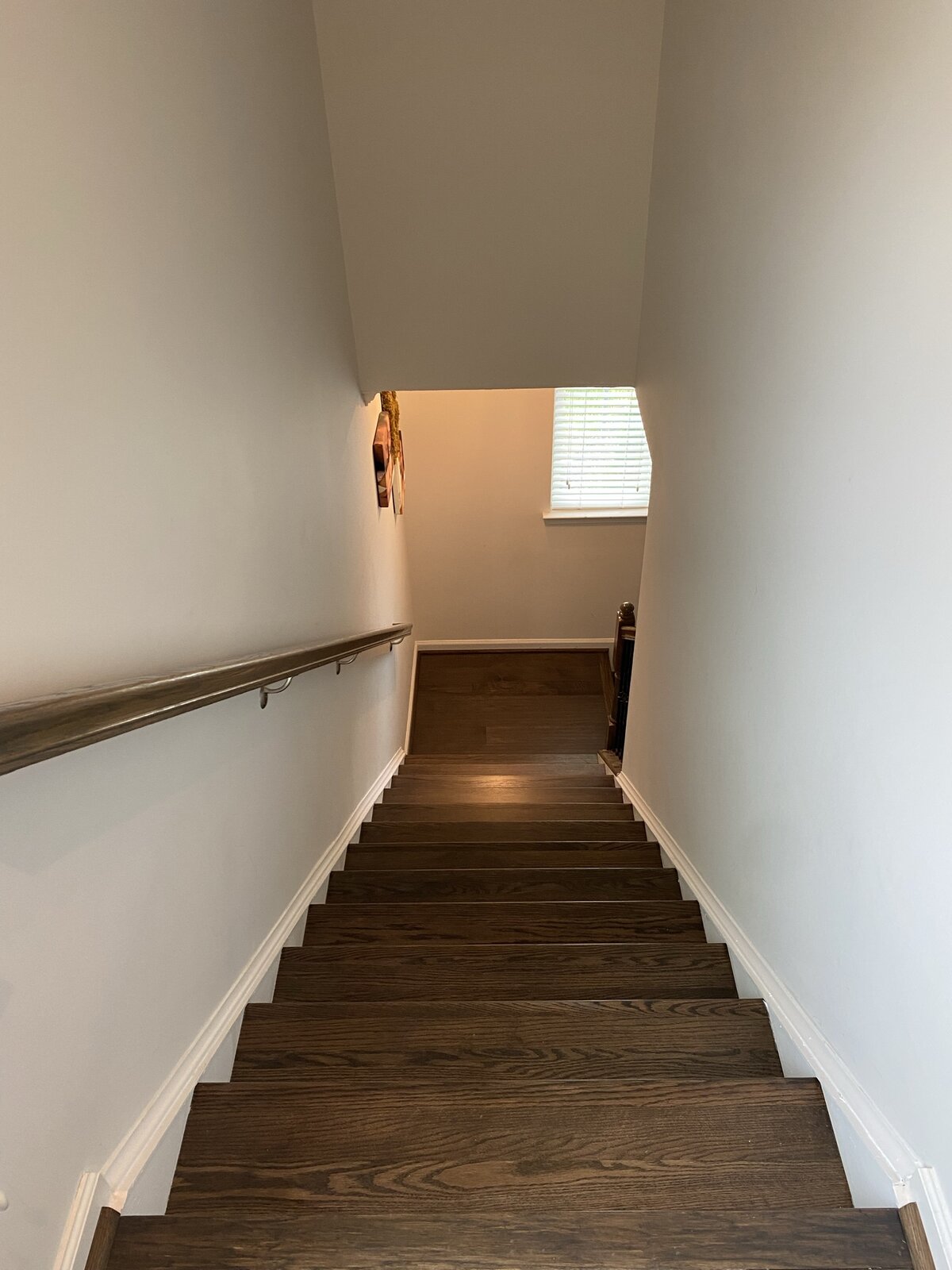 Detail of finished staircase — close view of stained oak tread meeting white riser, twisted iron baluster anchored cleanly to tread