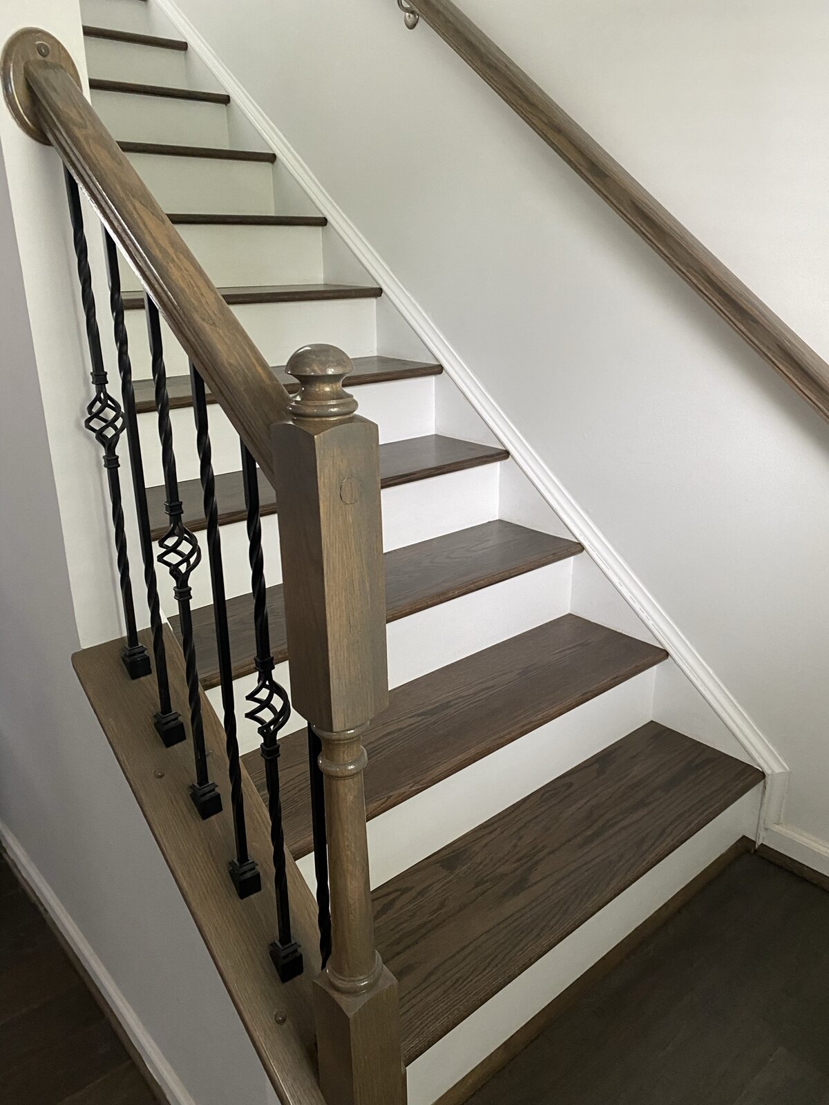 Hero detail — twisted wrought-iron balusters paired with a carved oak newel post, hand stained to match the treads